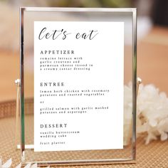 a menu card sitting on top of a table with white flowers in front of it