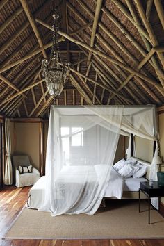 a bedroom with a canopy bed and chandelier hanging from it's ceiling