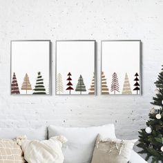 three canvases hanging on the wall above a couch with pillows and a christmas tree