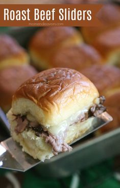 roast beef sliders on a serving tray with a spatula in the foreground