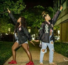 two people are standing on the sidewalk with their arms in the air and one person is wearing red shoes