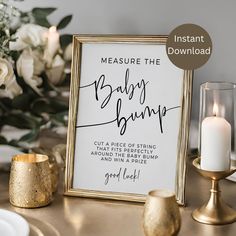 a baby bump sign sitting on top of a table next to some candles and flowers