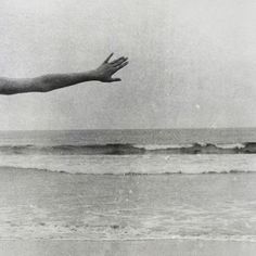 a hand reaching out towards the ocean