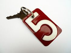 a red and white keychain with the letter c on it's side