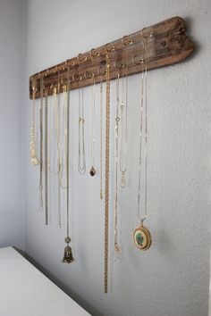 a wooden rack with many necklaces hanging from it's sides on a wall