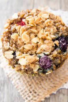 a muffin topped with blueberries and granola sitting on top of a napkin