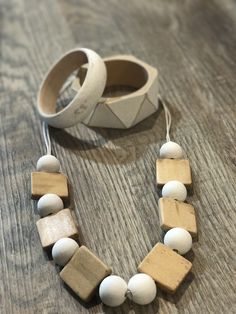 two bracelets are sitting next to each other on a wooden table with white beads