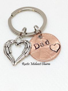 two key chains with an angel wing and heart on one side, the other has a dad's coin in the middle