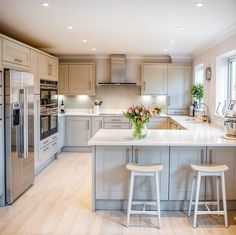 a large kitchen with two stools in front of the counter and an island that has flowers on it