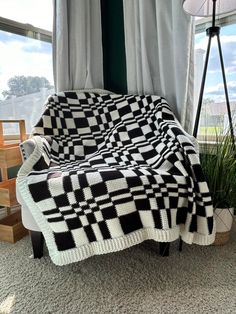 a black and white checkered blanket sitting on top of a couch next to a window