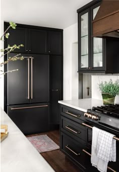 a kitchen with black cabinets and white counter tops, gold trimmings on the doors