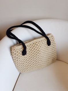 a handbag is sitting on top of a white chair with a black cord around it