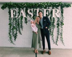 a man and woman standing next to a baby in front of a sign that says easter