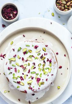 a white plate topped with a cake covered in frosting and pistachios