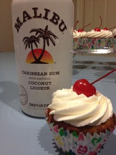 a cupcake next to a bottle of malibo rum on a white table