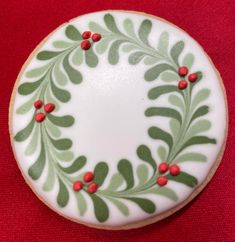 a decorated cookie with red berries and green leaves on the top is sitting on a red tablecloth