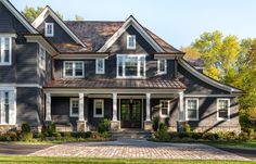 a large gray house with lots of windows and white trim on the front door is shown