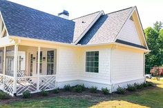 a small white house with a porch and covered in blue shingles on the roof