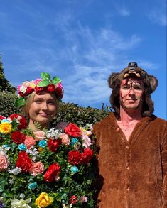 two people in costumes standing next to each other with flowers on their heads and one wearing a bear costume