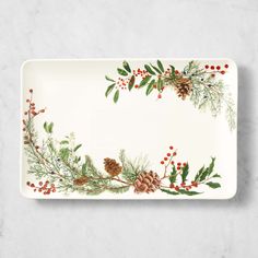 a white platter with holly and pine cones