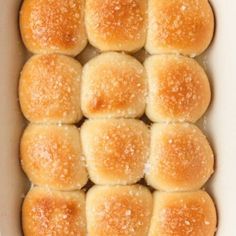 small rolls in a white baking dish with sugar on top, ready to be baked