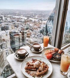 two plates of breakfast food on a table overlooking a cityscape with high rise buildings