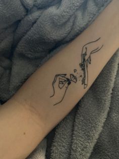 a woman's arm with a tattoo on it that has two hands holding something