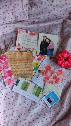 many different pictures and papers on a bed sheet with a pink flower in the middle