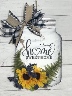 a mason jar with sunflowers and greenery on the front is decorated with an acrylic sign that says, home sweet home