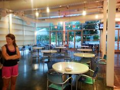 a woman standing in a room with tables and chairs