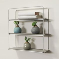 three white shelves with vases and towels on them