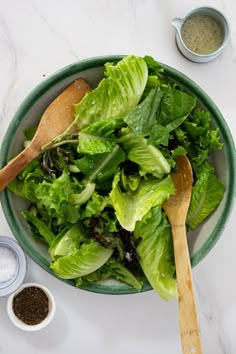 a bowl filled with lettuce and wooden spoons