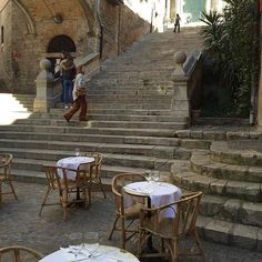 several tables and chairs with white tablecloths on them in front of stone steps