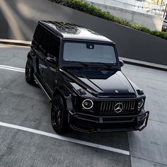 a black mercedes g - class is parked in a parking lot