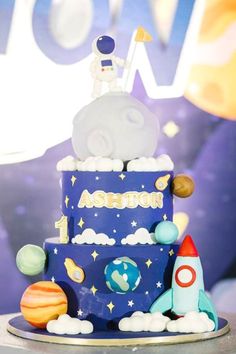 a birthday cake with an astronaut on top and planets around the edges, in front of a backdrop