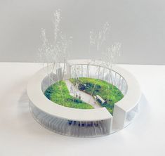 a model of a circular building with trees in the center and grass on the ground