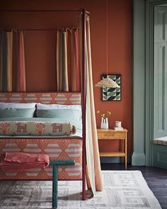 a bedroom with an orange wall and colorful bedding