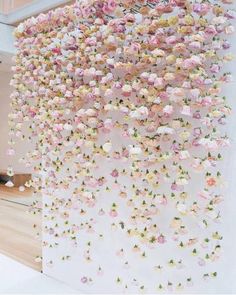 pink and yellow flowers are hanging from the ceiling in front of a white wall with stairs