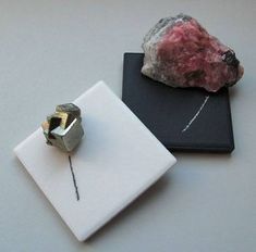 there is a rock on the table next to a small piece of jewelry that is sitting on top of a book