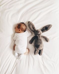 a baby sleeping next to a stuffed rabbit