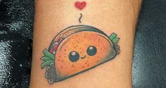 a taco with a heart on it is sitting on the arm, next to a black table