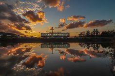 the sun is setting over a body of water with clouds in the sky above it