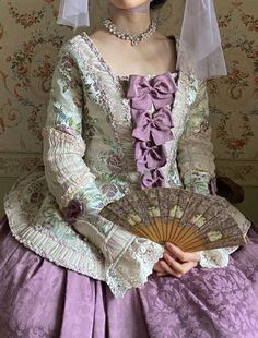 a woman wearing a purple dress and holding a fan