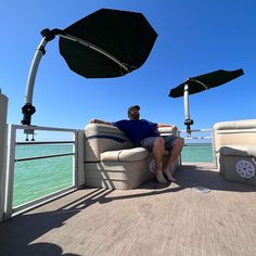 a man sitting on top of a boat under an umbrella