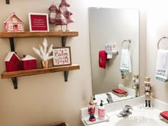 a bathroom decorated for christmas with red and white decorations on the shelf above the sink