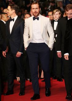 a man in a tuxedo walks down the red carpet