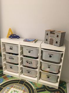 a toy car is sitting on top of a white shelf next to some plastic bins