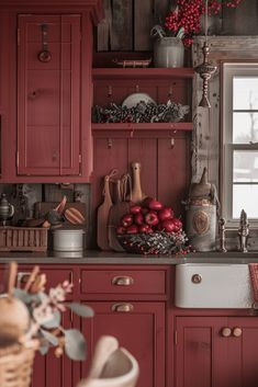 a kitchen with red cabinets and wooden shelves filled with christmas decorations on top of them