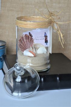 a glass jar filled with sand and shells