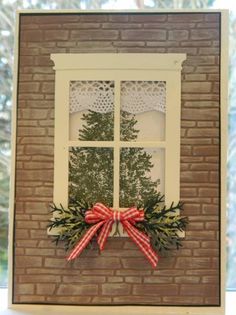 a window with a red bow on it and a tree in the window sill